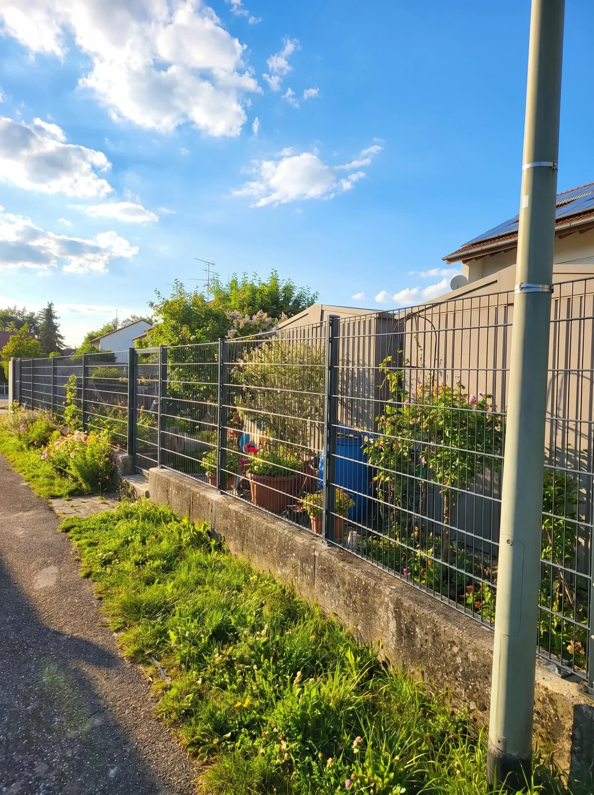 Anthrazitfarbener Doppelstabzaun entlang eines Gartenwegs